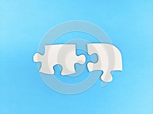 Two unconnected puzzle pieces on blue coloured background. Problem solving, teamwork and the integration of different elements