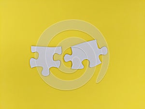 Two unconnected puzzle pieces on yellow coloured background. Problem solving, teamwork and the integration of different elements
