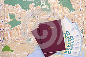 Two undefined passports with 20 euro banknotes money on top of a colorful local map. Concept for travel budget planning.