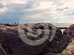 two undefined people walking on a rock by the sea in Sweden