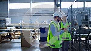 Two uniformed manufacture workers checking production process inspecting