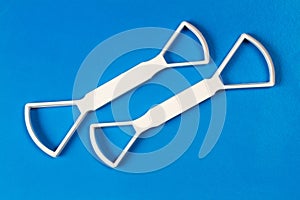 Two universal scrapers for cleaning the tongue on a blue background.