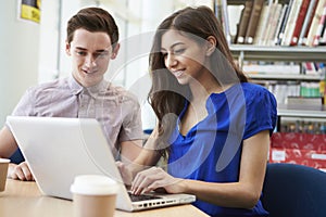 Two University Students Working In Library Using Laptop