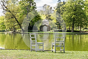 Two unoccupied wooden chairs overlooking a peaceful lake