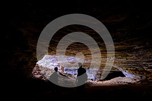 Two unrecognizable tourists at the entrance of Gruta Da Lapa Doce, cave in Iraquara, Chapada Diamantina, Bahia, Brazil