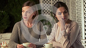 Two upset female friends sitting in cafe, relations conflict, misunderstanding