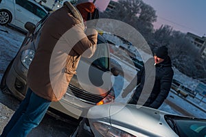 Two upset male drivers looking at damaged cars