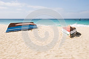 Two upturned boats on beach.