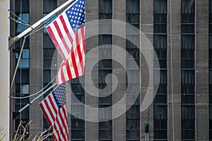 Two USA flags on the building facade with scyscrapper at the backgroumd. Symbol of America