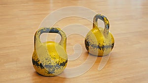 Two used and ruined yellow kettle bells.