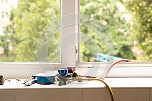 A two-valve manometric manifold lies on the windowsill in the apartment and measures the pressure in the air conditioner