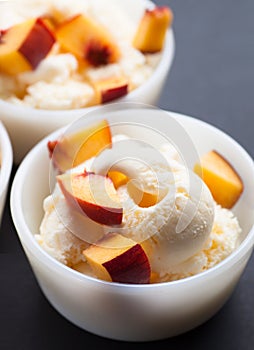 Two vanilla ice-cream with peach in white bowl