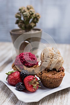 Two vegan cupcakes with berries and ice cream
