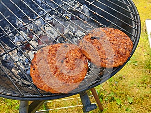 Two vegetarian burgers on a grill in the garden
