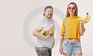 Two vegetarians holding fruit and vegetables