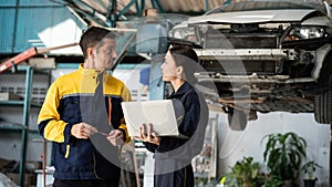 Two vehicle mechanic working together, conduct car inspection with laptop. Oxus
