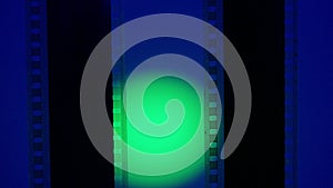 Two vertical film strips on a blue background with green circular light, close up. 35mm film slide frame. Long, retro