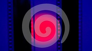 Two vertical film strips on a blue background with red circular light, close up. 35mm film slide frame. Long, retro film