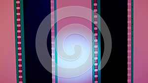 Two vertical film strips on a pink background with white circular light, close up. 35mm film slide frame. Long, retro