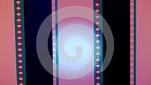 Two vertical film strips on a pink background with white circular light, close up. 35mm film slide frame. Long, retro