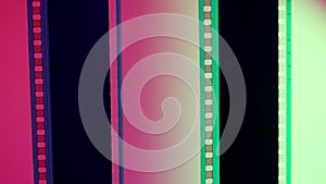 Two vertical film strips on a pink and white gradient background, close up. 35mm film slide frame. Long, retro film