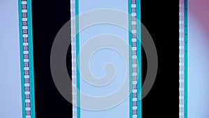 Two vertical film strips on a white and pink gradient background, close up. 35mm film slide frame. Long, retro film