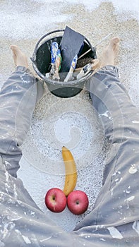 Two very suggestive red apples and a banana between the legs of a house painter with paint-stained pants