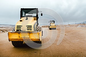 Two Vibratory Soil Compactors on construction site. Industrial roadworks at highway with heavy-duty machinery