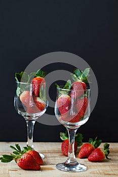 Two vine glasses filled with fresh strawberry on wooden table