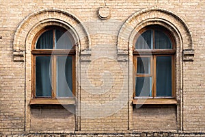 Two vintage arched windows in a wall of yellow bricks. Green - the colors of sea wave glass in a maroon dark red wooden