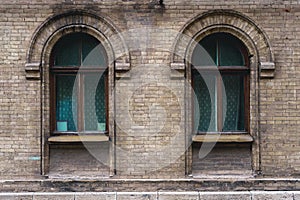 Two vintage arched windows in a wall of yellow bricks. Green - the colors of sea wave glass in a maroon dark red wooden