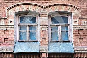 Two vintage arched windows in a wall of yellow bricks. Green - the colors of sea wave glass in a maroon dark red wooden