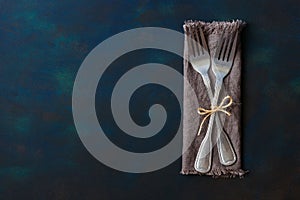 Two vintage forks tied with linen thread on a blue background. Space for text, lay flat