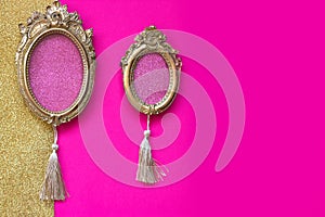 Two vintage golden oval picture frames on pink and golden background, with copy space in the frame