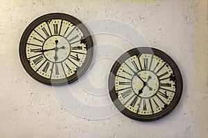 Two vintage old mechanical watches with roman numerals on a gray white concrete wall