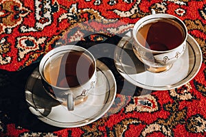 Two vintage porcelain cups of coffee or tea on the oriental turkish or asian carpet, tea ceremony