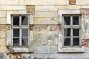 Two vintage windows in a white wooden frame on a grunge damaged wall.