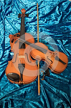 Two violins of different sizes on blue fabric