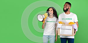 Two Volunteers Holding Donation Box Collecting Clothes Over Green Background