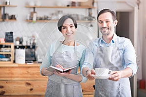 Two waiters in aprons standing in cafe