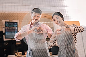 Two waiters wearing striped aprons standing near the entrance to restaurant