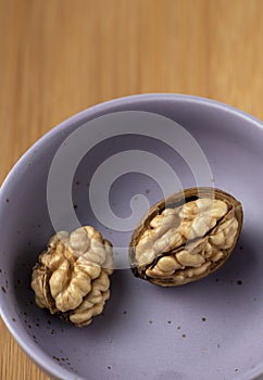 Two walnut in a violet plate on a wooden background on top view Still life photography