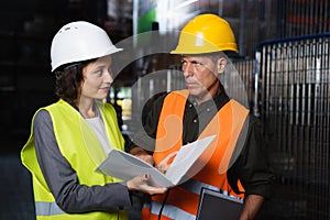 Two warehouse workers discussing logistics while