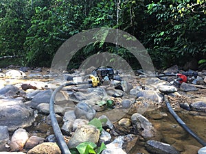 Two waterpumps to pump water for gold mining, the dirt flushes away in the river at the background