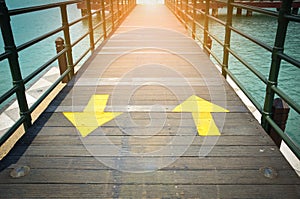 Two way yellow traffic arrows sign pointing to two direction on wooden bridge