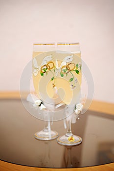 Two wedding glasses of champagne stand on the table