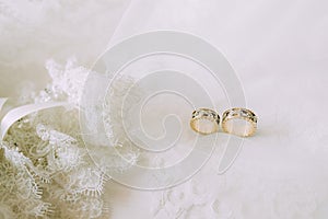 Two wedding gold rings on beautiful white tulle with lace garter close