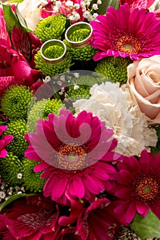 Two wedding rings on a bridal colorful bouquet