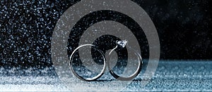 Two wedding rings in infinity sign with sparkling light mist. Love concept on black background. Wide panoramic