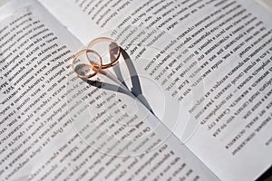 Two wedding rings lie in the book and create a heart from the shadow